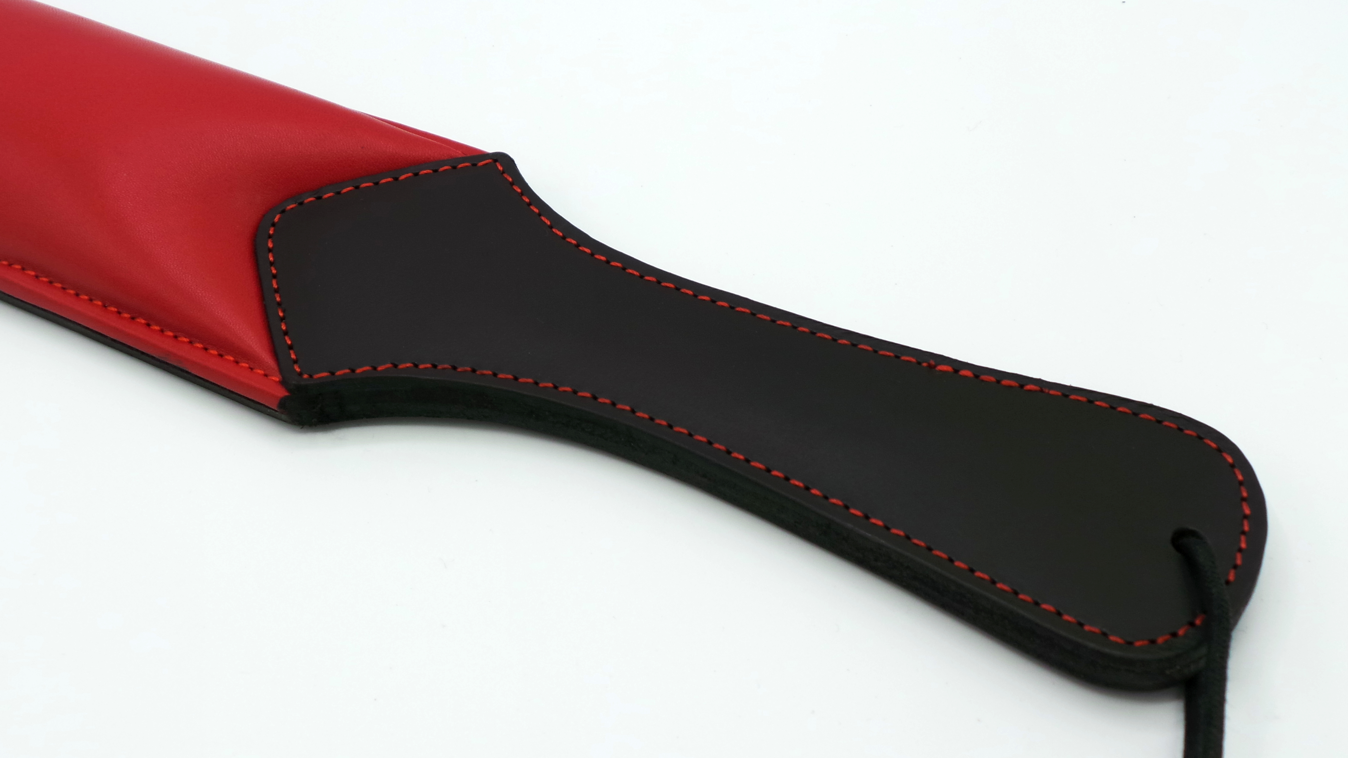 addel mit roter Ziernaht – Schwarz-Rot Detailansicht des Griffs eines gepolsterten Rindsleder-Paddels in Schwarz mit roter Ziernaht und roter Schlagfläche.