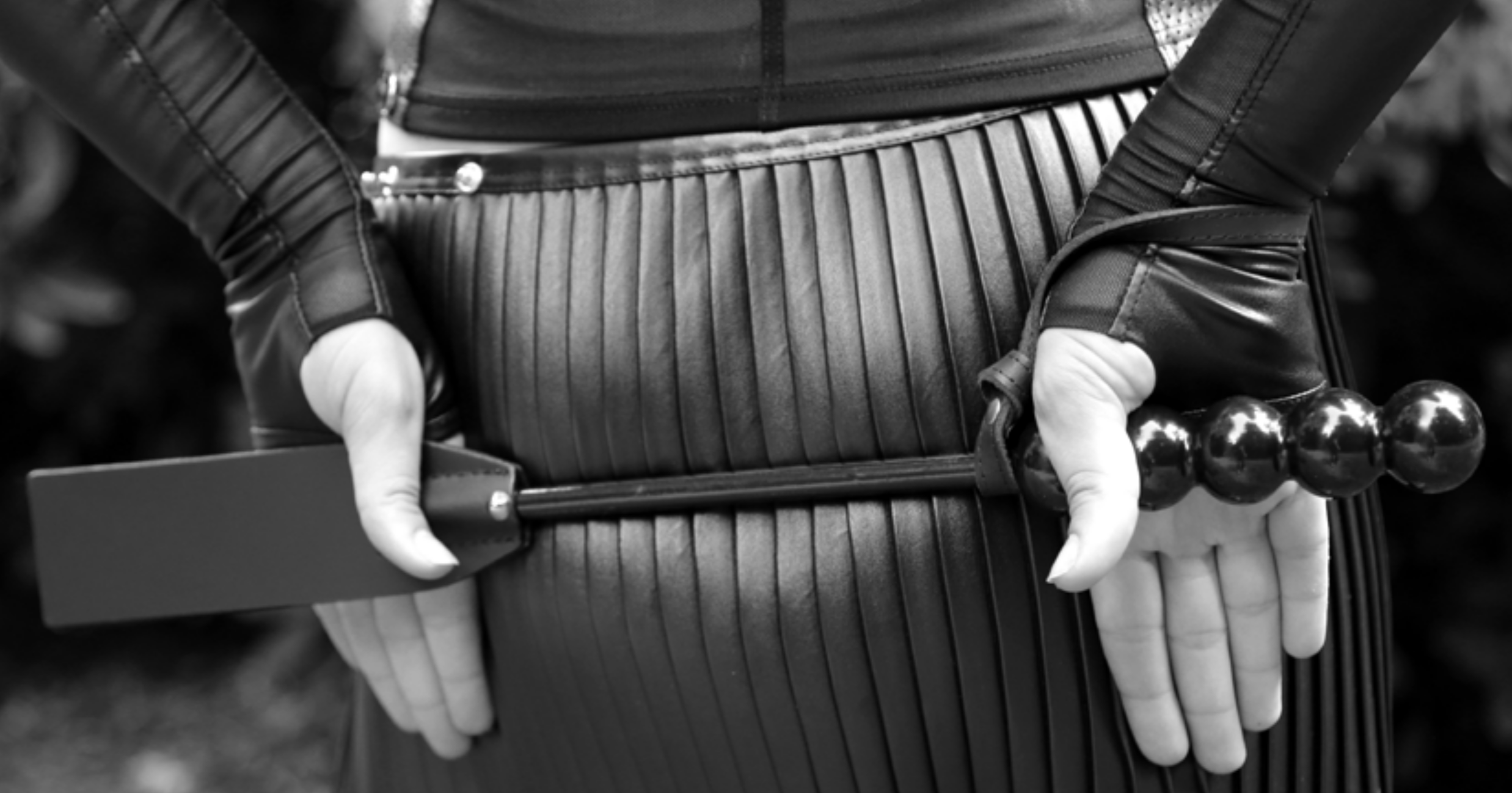 Frau in Lederkleidung hält eine BDSM-Peitsche